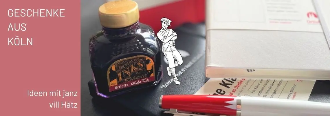 Kölsches Tintenfass, kölsche Kladde und ein kölscher Füllhalter von Ortloff auf einem Schreibtisch. Text "Geschenke aus Köln, Ideen mit janz vill Häzt"