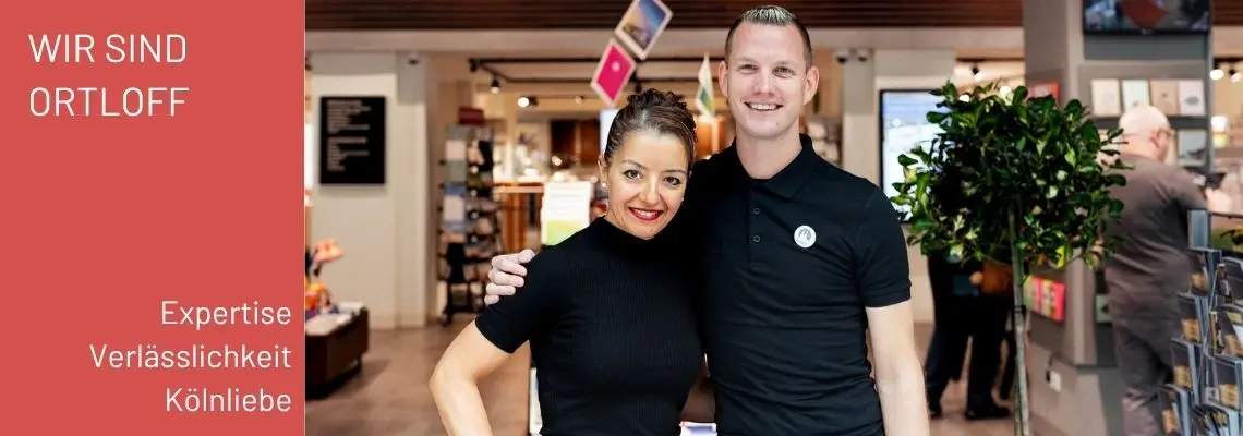 Zwei Mitarbeitende von Ortloff in Köln blicken lächelnd in die Kamera. Dazu der Text "Wir sind Ortloff, Expertise und Verlässlichkeit"