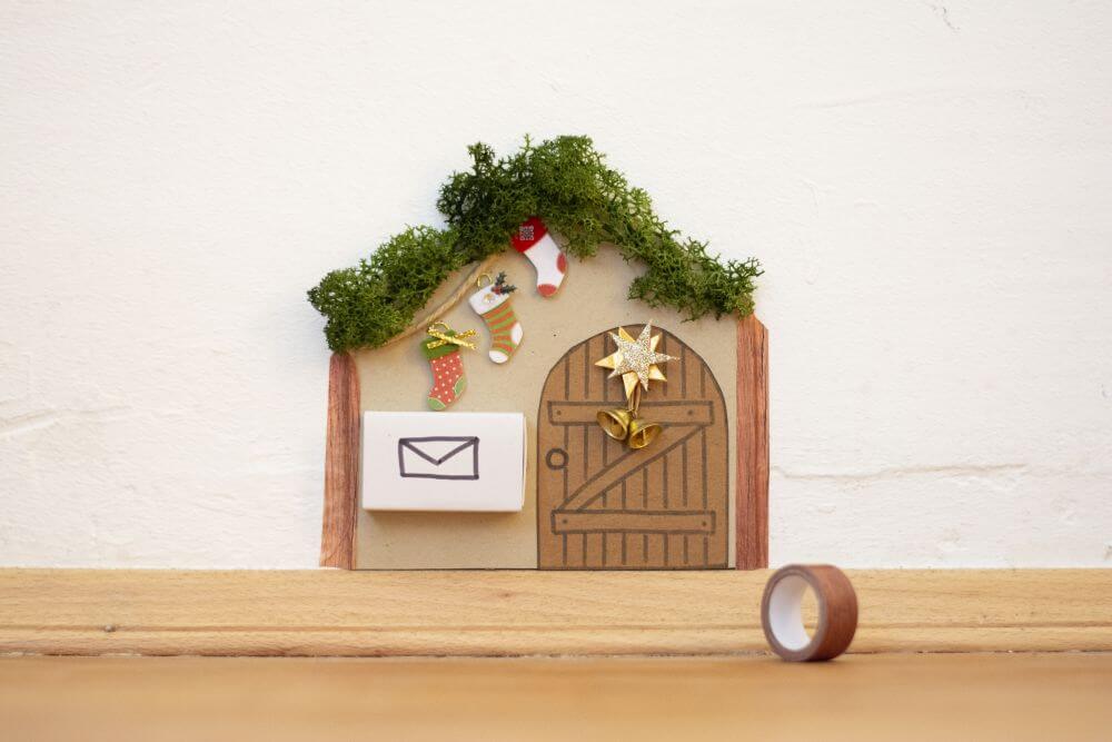 Wichteltür zu Weihnachten basteln, Bastelanleitung Schritt 8: Die Wichteltür mit Hilfe von Dekotape in Holzoptik von Heyda an der Wand befestigen.