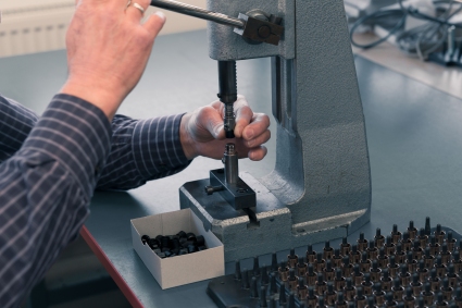 Jemand montiert einen Teil eines Füllers per Hand in eine Maschine.