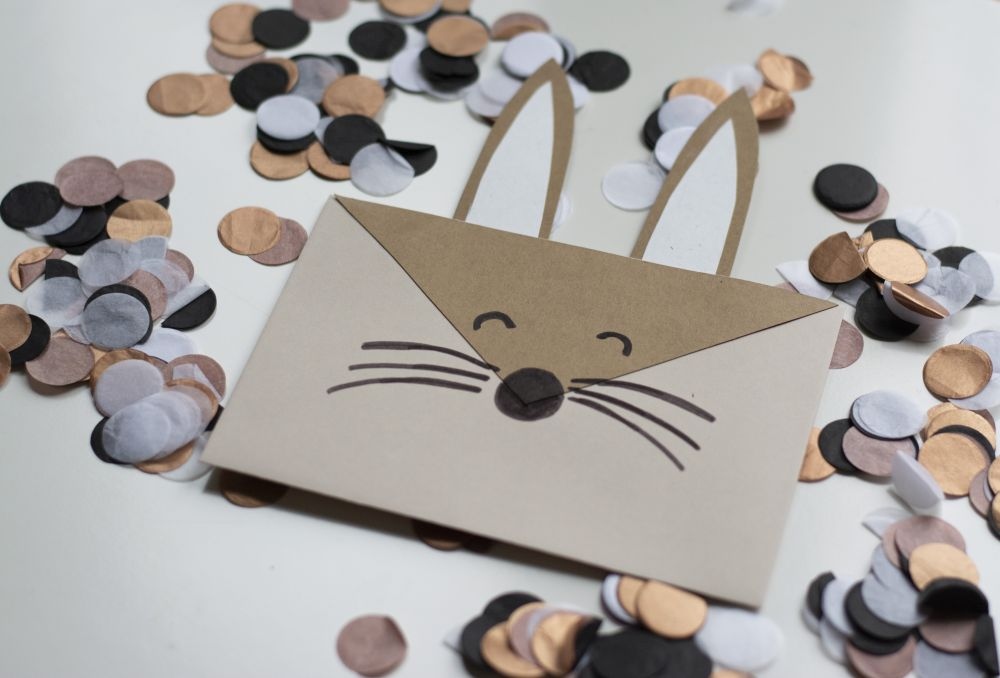 Einladungskarte zum Kindergeburtstag: Selbst gebastelte Do it yourself-Karte als Hase liegt auf Konfetti