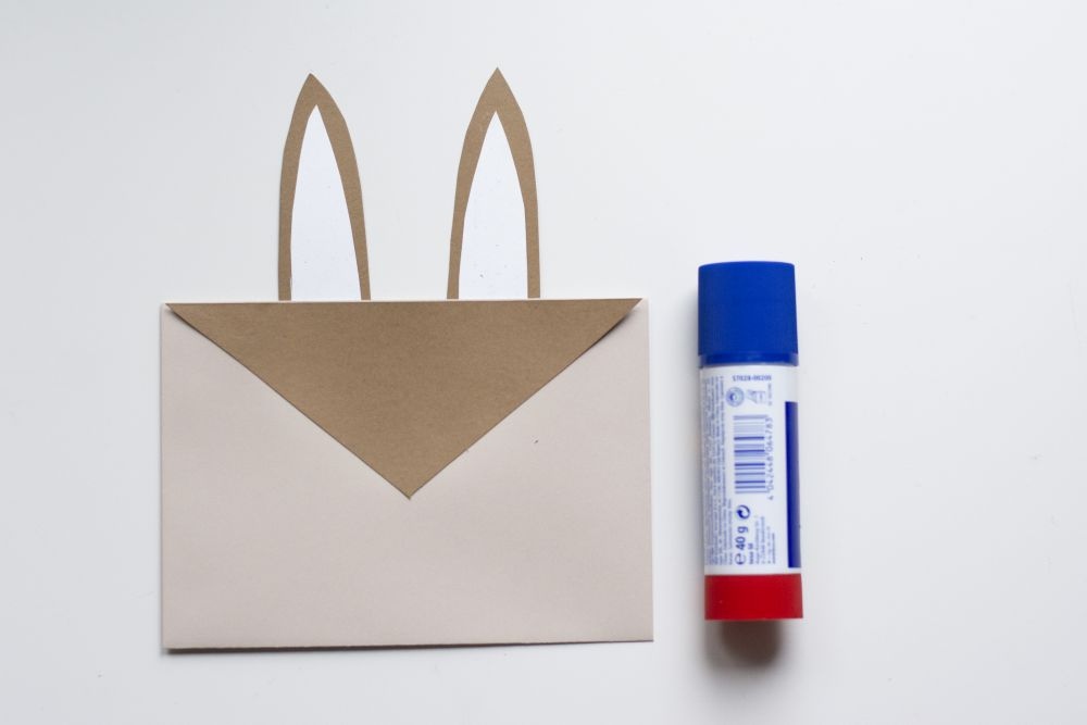 Bastelanleitung Einladungskarte zum Kindergeburtstag: Selbst gebastelte Do it yourself-Karte als Hase, Schritt 2: Papierzuschnitte sind mit Klebstoff auf einen Briefumschlag geklebt.