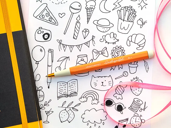 Neben einem gelben Bullet Journal von LEUCHTTURM1917 liegt eine ausgedruckte Vorlage mit verschiedenen Doodles zum Abpausen. Foto: Johanna Rundel