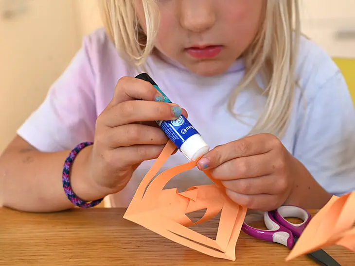 Ein Kind bastelt mit Papier und Kleber von Pelikan einen Stern. Foto: Johanna Rundel