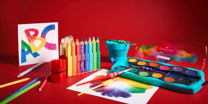Auf bunten Papieren liegen diverse Schulmaterialen von Faber-Castell verstreut.