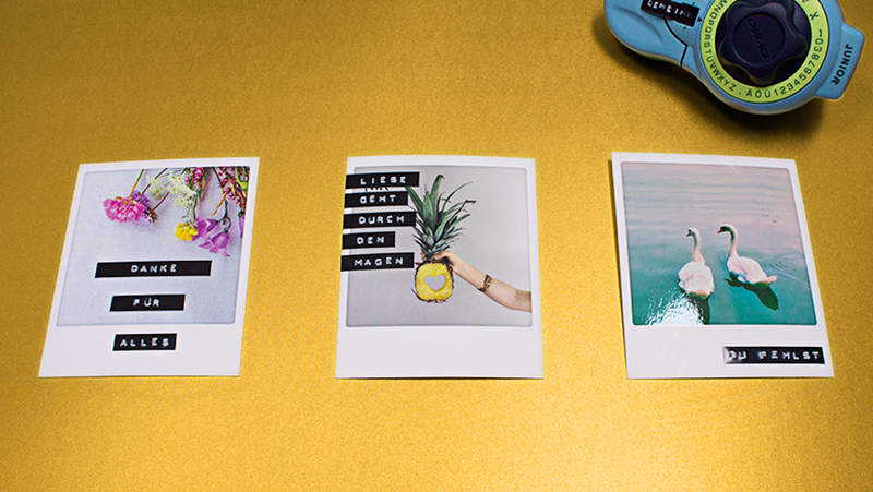 Auf einem gelben Untergrund liegen drei Grußkarten im Vintagestil. Diese sind als Polaroid-Fotos aufgemacht. Die Motive wurden mit Sprüchen ergänzt. Diese wurden mit einem Prägegerät von Dymo erstellt. Das Prägegerät ragt oben links ins Bild.