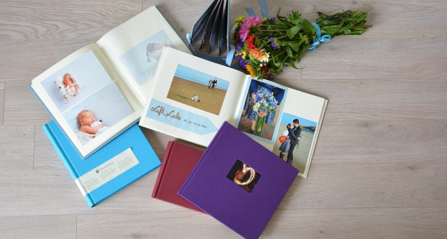 5 Fotoalben von Semikolon liegen auf dem Tisch. 2 Fotoalben sind offen. In einem Fotoalbum ist das Baby zu sehen im anderen das verliebte Pärchen.