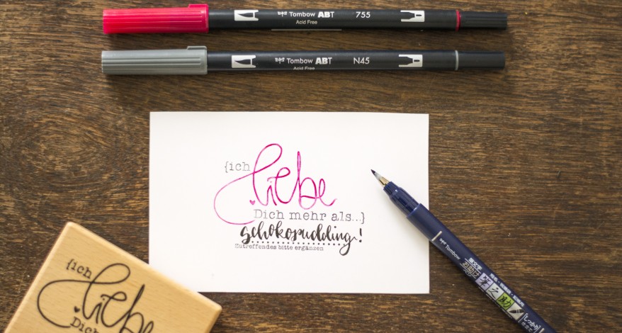 Karte mit Handlettering „Ich liebe dich mehr als Schokoladenpudding…“ und Tombow-Stiften.