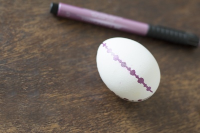 Ei mit lilafarbenem Punktmuster auf Holztisch