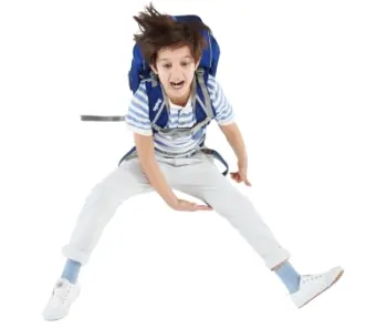 Ein Junge im Grundschulalter mit einem ergobag Schulranzen auf dem Rücken macht einen Sprung.