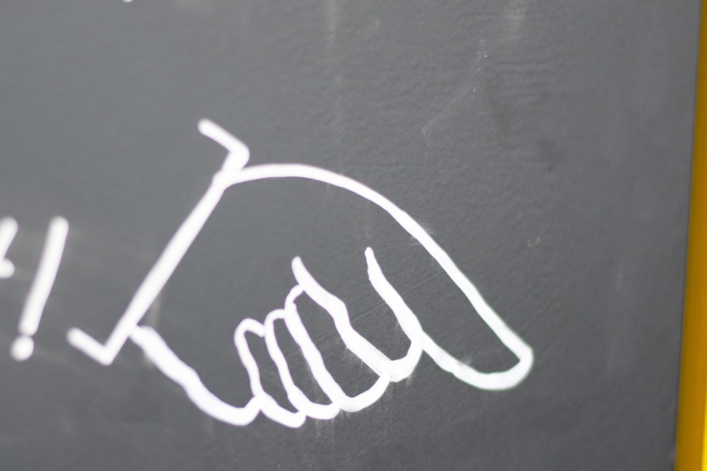 Kreidezeichnung einer weißen Hand, die nach unten zeigt