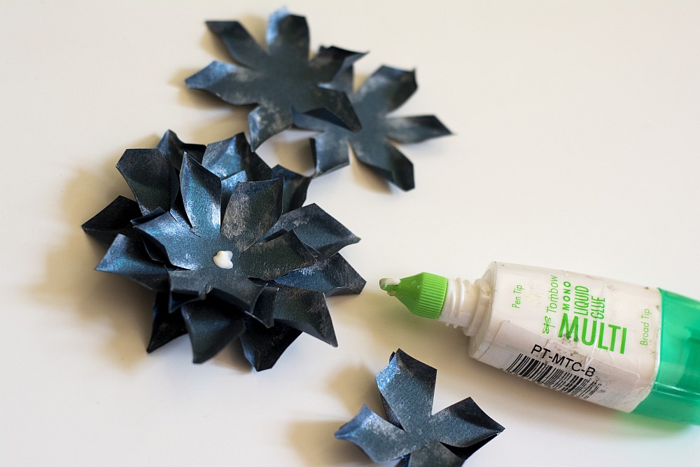 Papierblüten werden mit Flüssigkleber zusammengesetzt