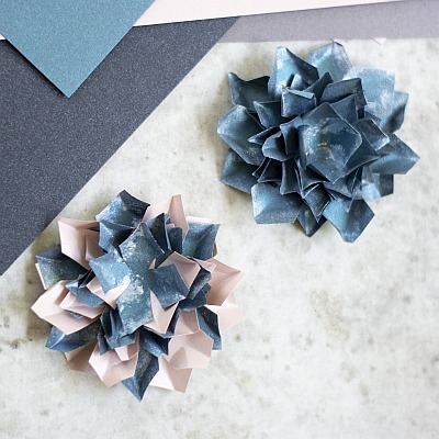 Detailaufnahme gefalteter Papierblumen in blau und rosa-blau