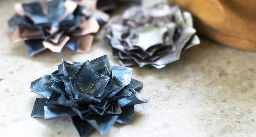 Zwei gefaltete Papierblumen aus blauem und rosa Bastelpapier