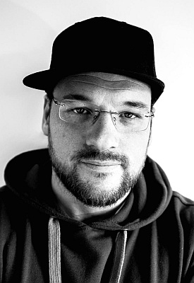 Porträt eines Mannes mit Brille, Bart und schwarzer Kappe