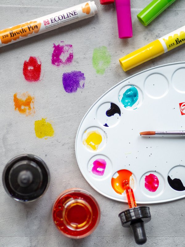 Farbpalette mit Aquarelltropfen, einem Pinseln, Brushpens und Aquarellfarbe von Ecoline.