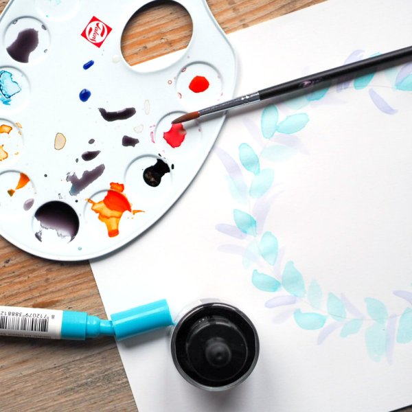 Mischpalette mit Aquarellfarben von Ecoline und einem Pinsel auf Papier.