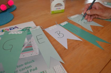 Selbstgestaltete Geburtstags-Girlande mit grünen Wimpeln in der Entstehung.