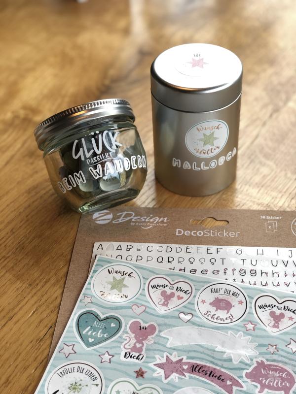 Zwei mit Stickern beklebte Dosen stehen auf einem Holzboden. Daneben liegen Deco-Sticker von Z-Design.