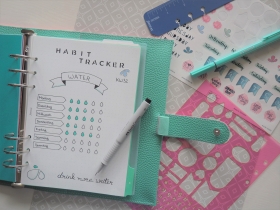 Offener Ringbuch-Planer mit Wasser-Trinktracker und Deko.