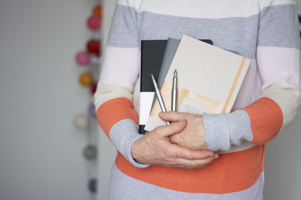 Frau hält Notizbücher, Kugelschreiber und Füllhalter von Hahnemühle im Arm.