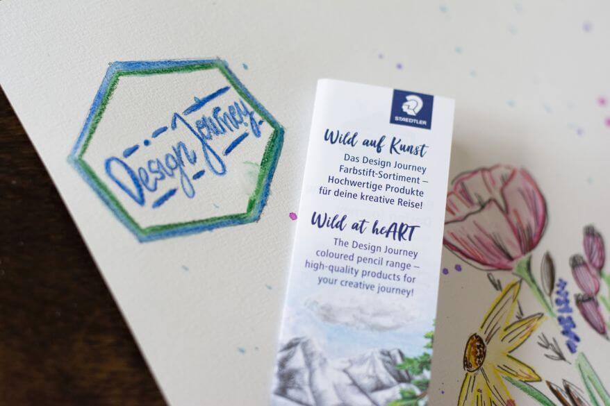 Detailaufnahme des nachgemalten Logos der Design Journey von Staedtler. Auf einem Produktblatt steht der Text "Wild auf Kunst".