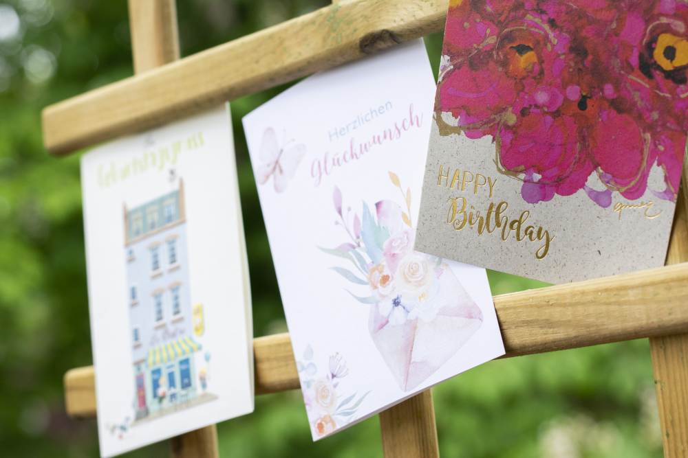 Verschiedene Glückwunschkarten zum Geburtstags von ABC Cards hängen an einem Rankgitter.