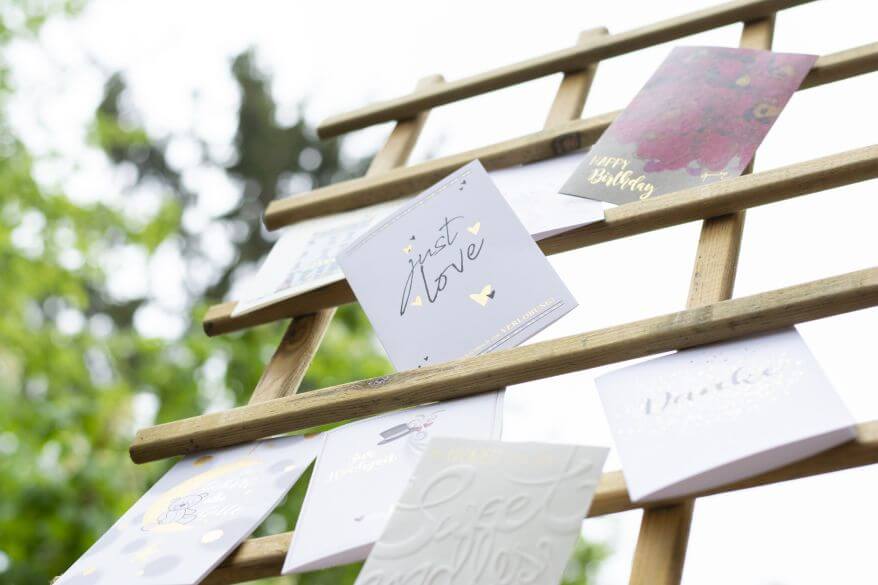 Verschiedene Grußkarten sind an einem Rankgiter festgeklemmt. Auf einer Postkarte steht "just love".