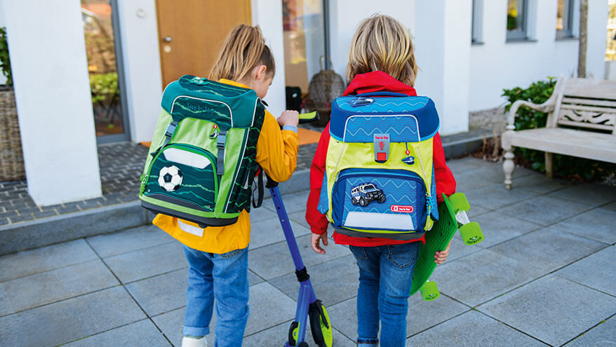 Zwei Grundschulkinder mit jeweils einem Step by Step Schulranzen auf dem Rücken kommen von der Schule zuhause an.