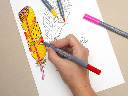 Jemand malt mit gelben, orangenen und roten Fasermaler von Faber-Castell eine Vogelfeder aus. Foto: Johanna Rundel