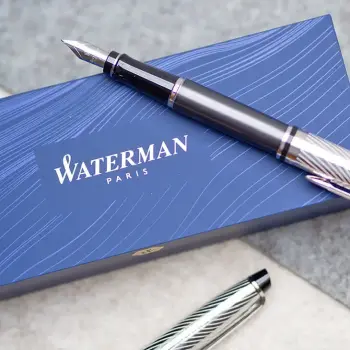 Auf einer hellgrauen Filzmatte liegt ein blaues Schreibgeräte-Etui von Waterman. Darauf und daneben liegen zwei edle Füllfederhalter. Foto: Johanna Rundel
