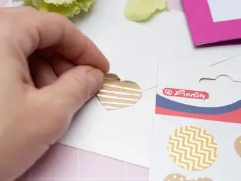 Jemand klebt ein Herzsticker von herlitz auf die Rückseite eines Briefumschlags. Foto: Johanna Rundel