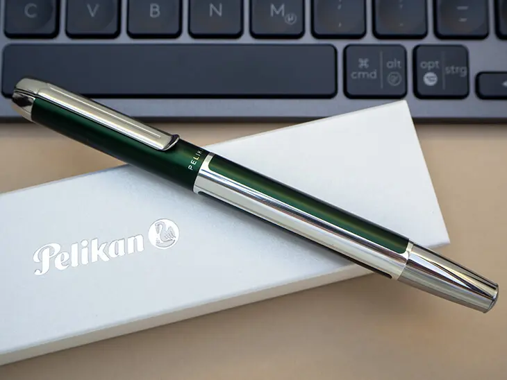 Ein dunkelgrüner Pura-Füller von Pelikan liegt auf einer weißen Geschenkbox mit silbernem Pelikan-Schriftzug vor einer schwarzen Tastatur. Foto: Johanna Rundel