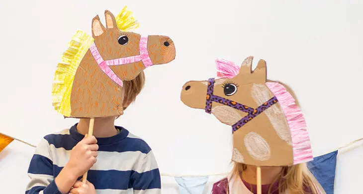Zwei Kinder halten selbstgebastelte Steckenpferde vor ihre Gesichter. Foto: Johanna Rundel