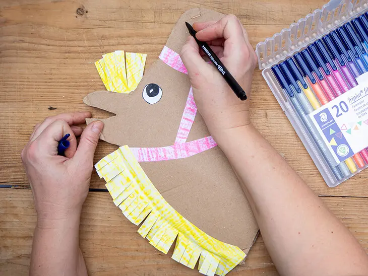 Jemand malt mit Filzstiften von STAEDTLER Details auf einen DIY-Pferdekopf aus Pappe. Foto: Johanna Rundel)