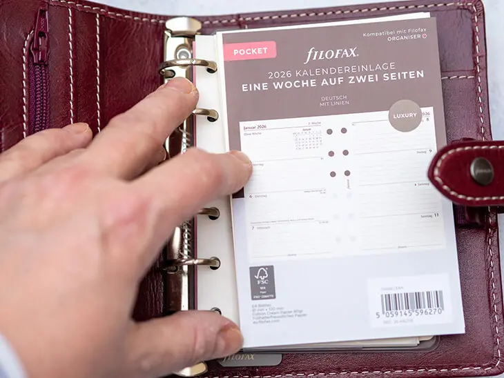 Jemand legt einen neuen Kalender in einen roten Filofax Pocket ein. Foto: Johanna Rundel