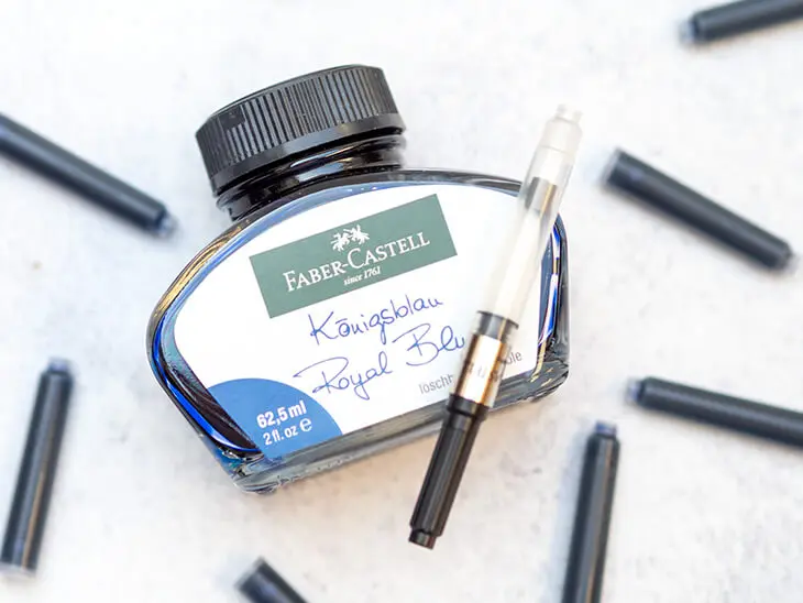 Ein Tintenfass, darauf ein Konverter umgeben von Tintenpatronen von Faber-Castell. Foto: Johanna Rundel