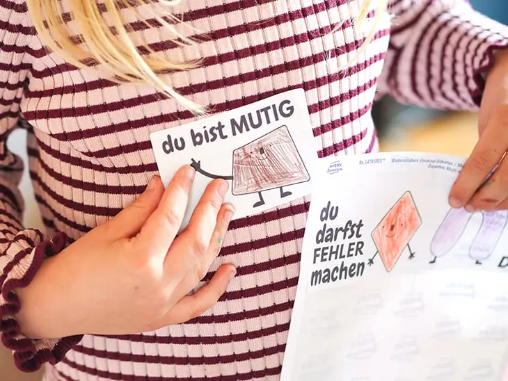 Einem Kind klebt sich ein Mutmach-Sticker von Avery Zweckfrom auf die Brust. Foto: Johanna Rundel