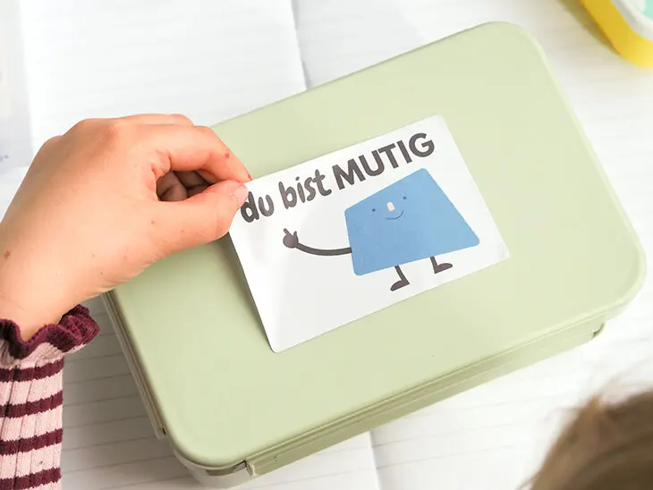 Kind klebt Mutmach-Sticker von Avery Zweckform auf Brotbox. Foto: Johanna Rundel