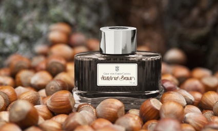 Ein Tintenfass von Graf von Faber-Castell steht in ausgebreiteten Haselnüssen.