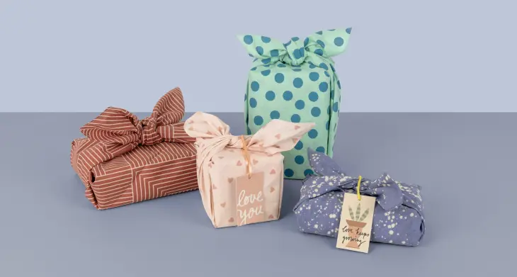 Geschenke, eingepackt in Furoshiki-Tücher von Stewo, stehen auf einem Tisch