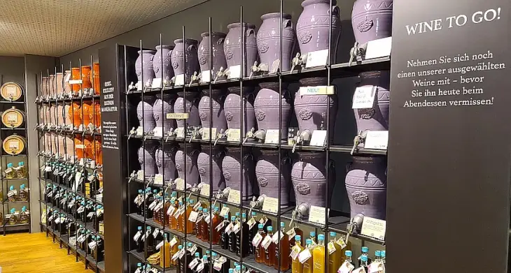 Eine Wand mit bunten Keramik-Weinfässern und Essigflaschen