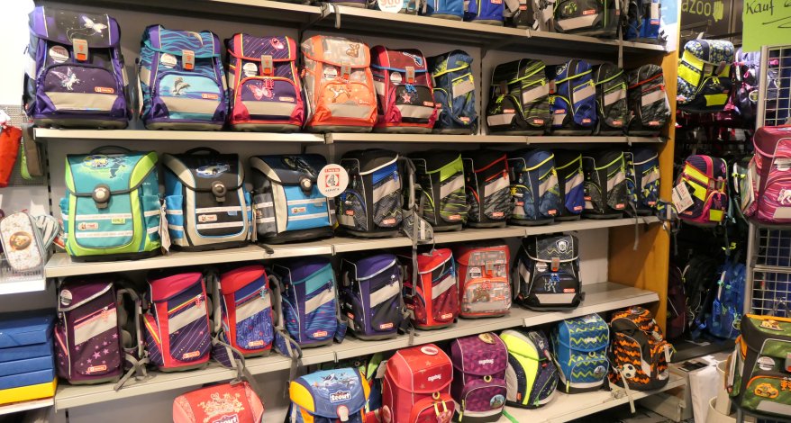 Viele bunte Schulranzen der Marken ergobag und Step by Step stehen im Regal.