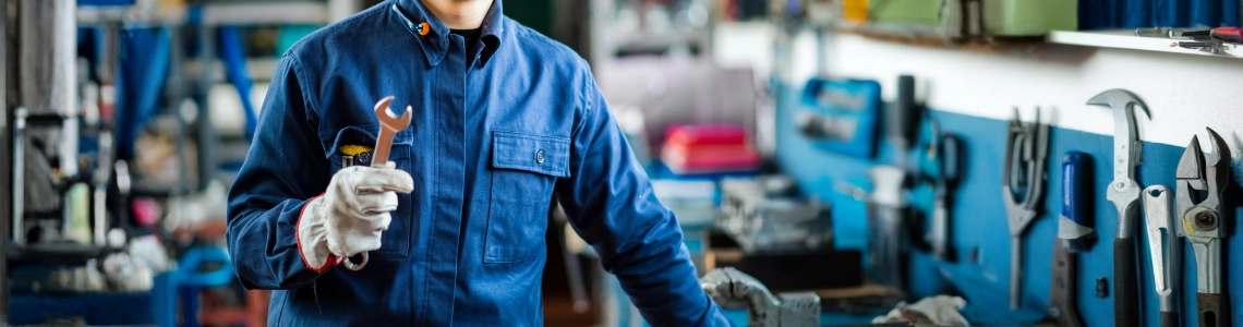 Mechaniker arbeitet in gut organisierter Werkstatt mit Werkzeugwand und Werkbank.
