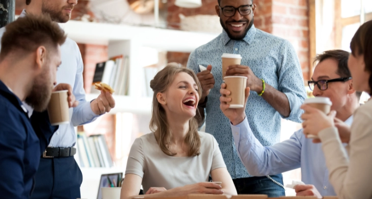Kollegen genießen gemeinsam Kaffee und lachen im Büro.