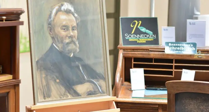 Historisches Gemälde des Unternehmers Friedrich Soennecken neben einem Soennecken-Schreibtisch