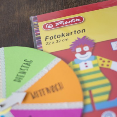 Teil einer Verpackung für Fotokarton der Marke herlitz. Darauf ist ein Teil des gebastelten Wochenplans mit den Tagen Dienstag und Mittwoch zu sehen.