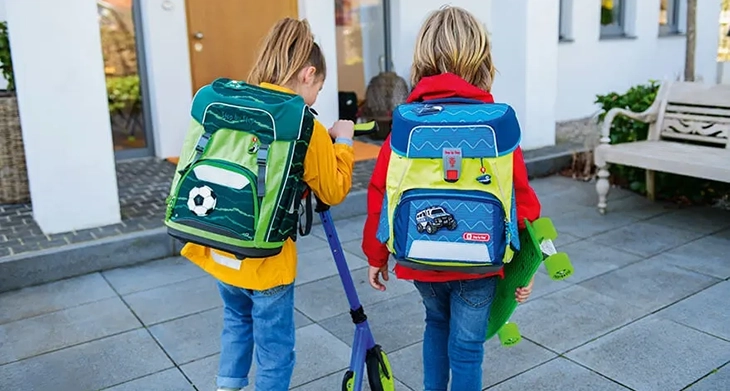 Zwei Grundschulkinder mit jeweils einem Step by Step Schulranzen auf dem Rücken kommen von der Schule zuhause an.