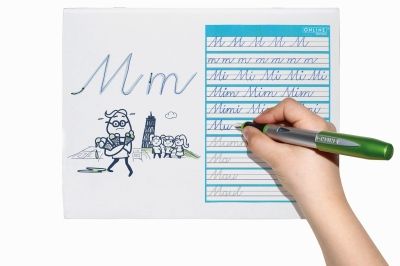 Kind übt Schreibschrift mit grünem Füller auf Übungsblatt.