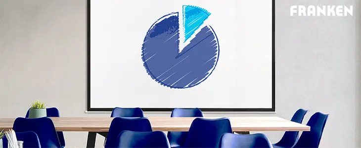 Das Bild zeigt einen modernen Besprechungsraum mit einem großen Tisch und blauen Stühlen. Im Hintergrund ist eine Leinwand zu sehen, auf der ein Diagramm projiziert wird. Die Umgebung wirkt hell und professionell.